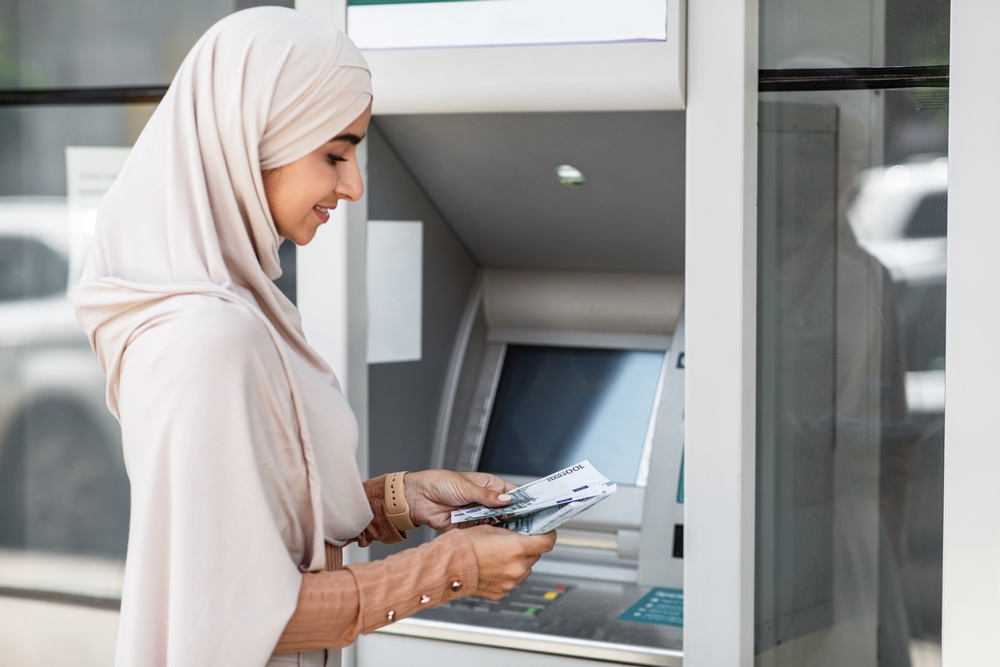 мусульманка у банкомата с деньгами