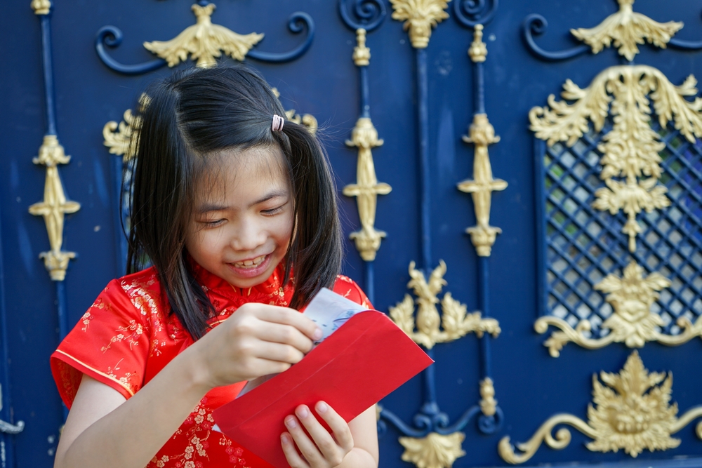 девочка в китае держит красный конверт с деньгами